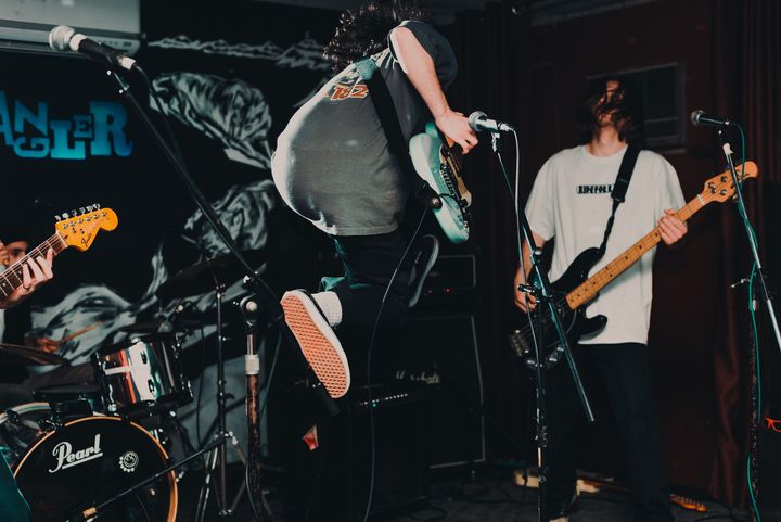 Band performing with guitarist mid-jump